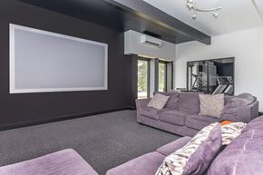 East Lansing townhouse for rent - A living room with a grey couch and a large empty white screen on the wall.