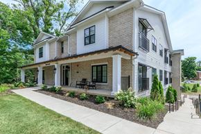 Bloomington apartment for rent - A house with a white and brown exterior and a black railing.