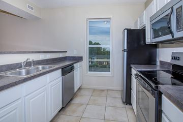 Bloomington apartment for rent - A kitchen with white cabinets and black appliances.