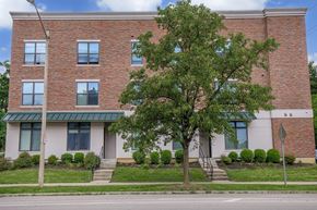 Bloomington apartment for rent - A red brick building with a green roof and a tree in front.