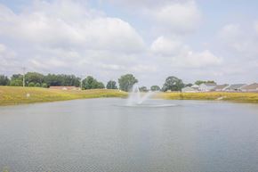 Lafayette apartment for rent - A fountain in the middle of a lake with houses and trees in the background.