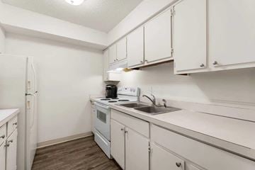 East Lansing apartment for rent - A small kitchen with white cabinets and a white fridge.