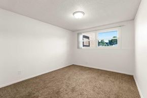 East Lansing apartment for rent - A room with a carpeted floor and a window showing a view of a building and trees.