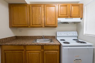 Atlanta townhouse for rent - a kitchen with a stove and a sink and wooden cabinets