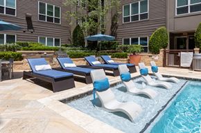 Houston apartment for rent - A pool with a blue umbrella and lounge chairs.