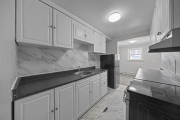 Ottawa apartment for rent - A kitchen with white cabinets and black countertops.
