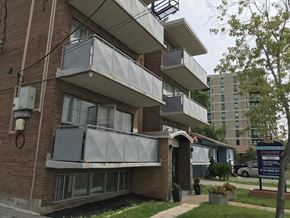 Toronto apartment for rent - a brick apartment building with three balconies and a sidewalk