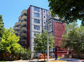 Toronto apartment for rent - an apartment building with a red and gray facade and trees