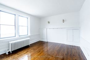 Toronto apartment for rent - bedroom with wood floors and white walls and a radiator and two windows