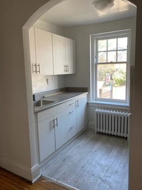 Toronto apartment for rent - an empty kitchen with white cabinets and a window