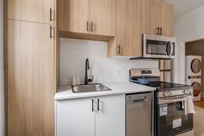Ottawa apartment for rent - A kitchen with a stainless steel dishwasher and white countertops.