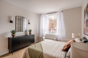 Ottawa apartment for rent - A bedroom with a bed, nightstand, and a window with curtains.