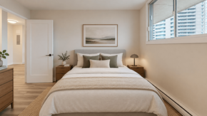 Ottawa apartment for rent - A bedroom with a large bed, a nightstand, and a painting on the wall.