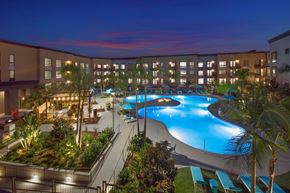 San Diego apartment for rent - A large outdoor pool surrounded by palm trees and plants at Purl Apartments, San Diego, 92108