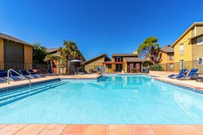 San Antonio apartment for rent - A swimming pool surrounded by lounge chairs and apartment buildings.