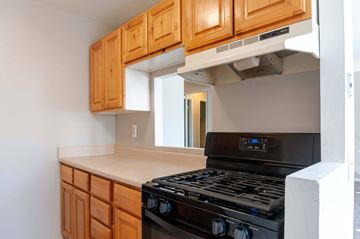 Feasterville-Trevose apartment for rent - A black stove top oven with a digital display is in a kitchen with wooden cabinets.