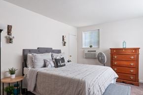 Magnolia apartment for rent - A bedroom with a bed, dresser, and window.