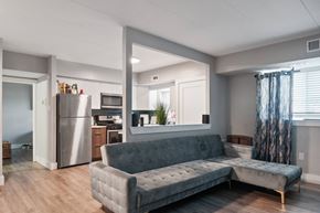 Philadelphia apartment for rent - A grey couch in a room with a kitchen in the background.