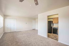 Baltimore apartment for rent - A room with a ceiling fan and a doorway leading to a kitchen.