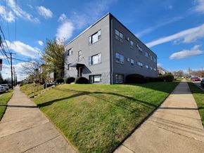 Philadelphia apartment for rent - A grey building with a green lawn in front.