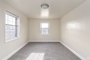 Baltimore apartment for rent - A room with a carpeted floor, a window, and a ceiling light fixture.