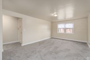 Baltimore apartment for rent - A room with a carpeted floor and a window with a view of trees outside.
