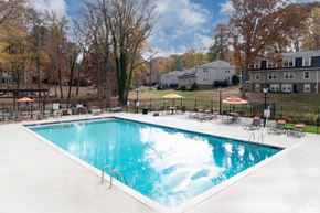 Greensboro apartment for rent - a pool with chairs and umbrellas next to a building