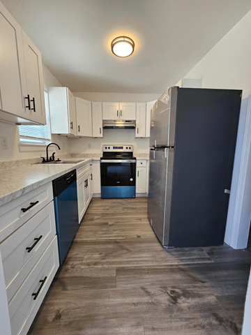 High Point apartment for rent - A kitchen with a black refrigerator and white cabinets.