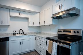 Charlotte apartment for rent - a kitchen with white cabinets and black appliances and a sink
