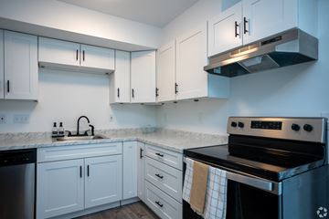 Charlotte apartment for rent - A kitchen with white cabinets and a black stove top oven.