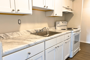 Farmingdale apartment for rent - A kitchen with white cabinets and a marble countertop.