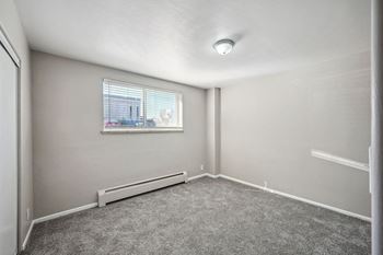An empty living room with a window and carpet