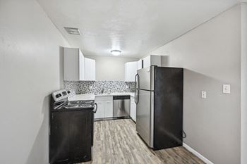 An empty kitchen with a refrigerator and a stove