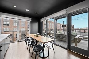 New Haven apartment for rent - a dining area with a wooden table and chairs and a large window with a balcony at The Audubon New Haven, New Haven, Connecticut