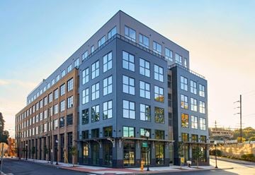 Norwalk apartment for rent - A modern multi-story building with large windows and a flat roof.