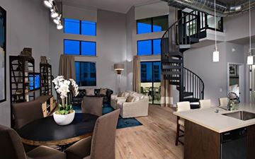 Phoenix apartment for rent - A modern living room with a spiral staircase and a dining table set for six.