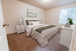 Lakewood apartment for rent - A bedroom with a large bed and a nightstand with a lamp at Bellamy Park Apartments , Lakewood, 98498