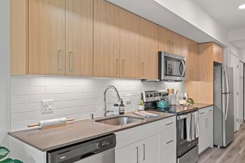 A kitchen with white cabinets and stainless steel appliances and a sink