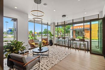 A living room with large windows and a table with chairs