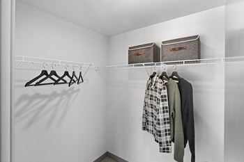 A walk in closet with two baskets on the wall and clothes hanging on a rack