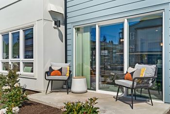 A patio with two chairs and a table outside a house