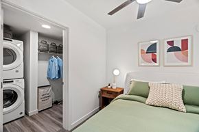 Seattle apartment for rent - A bedroom with a green bed and a washing machine in the closet.