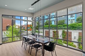 Seattle apartment for rent - A dining table with chairs is set up in a room with a view of a building and greenery outside.