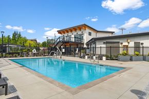 Tacoma apartment for rent - A large swimming pool in front of a building with a black fence around it.