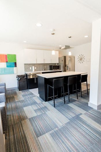 An open kitchen and living room with a bar and chairs