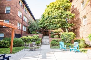 A patio with chairs and tables in front of a brick building