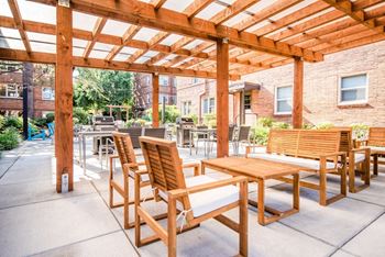A patio with wooden tables and chairs and a pergola