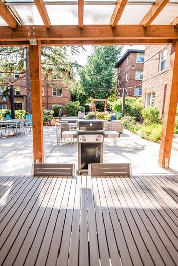 A patio with a grill and a table and chairs