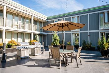 A patio with tables and chairs and an umbrella