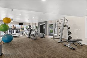 Puyallup apartment for rent - A gym with a variety of equipment including a treadmill, weights, and a bench.